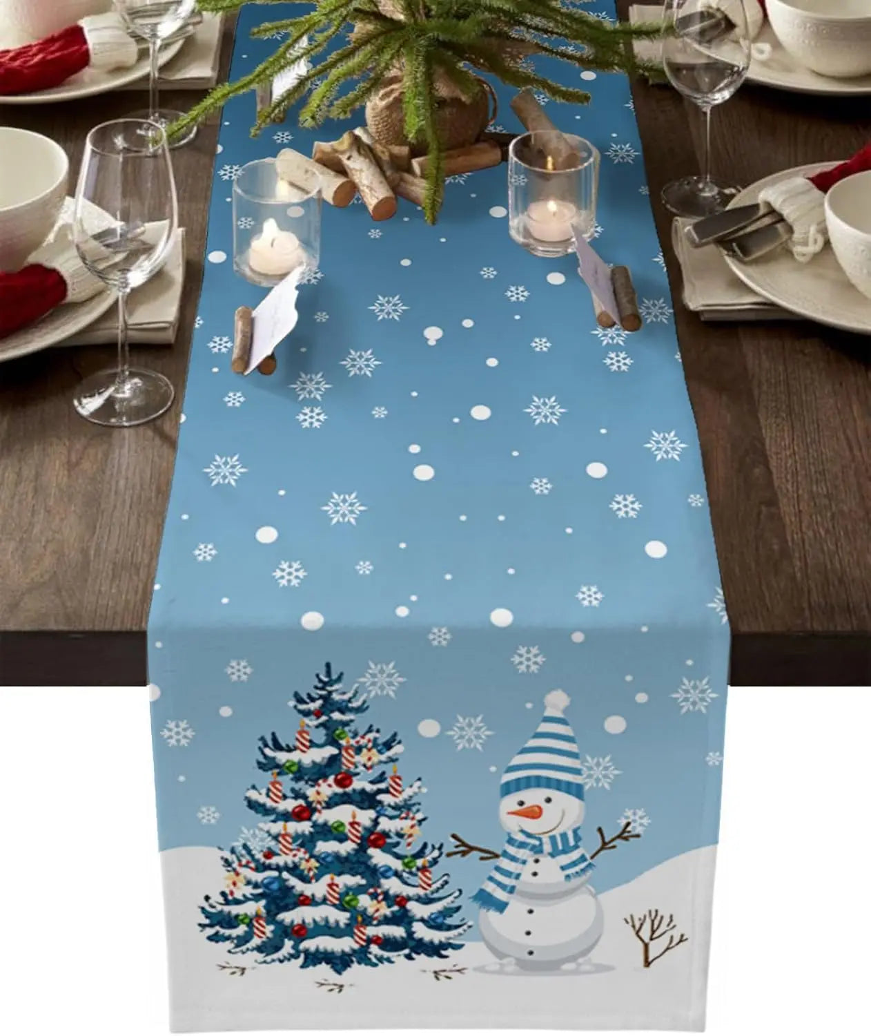 Une table de fête hivernale décorée avec un arbre de Noël illuminé, un bonhomme de neige et des flocons de neige sur fond bleu.
