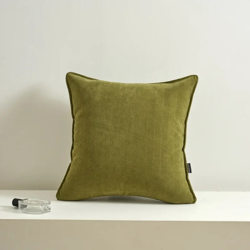 Coussin décoratif vert olive sur un support blanc.