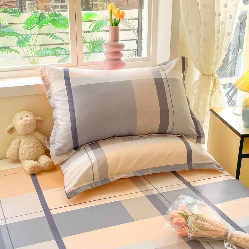 Deux oreillers rayés de couleurs douces sont placés sur un canapé, devant une fenêtre laissant voir des palmiers. Un ourson en peluche blanc est assis à côté, complétant cette scène de confort et de détente.