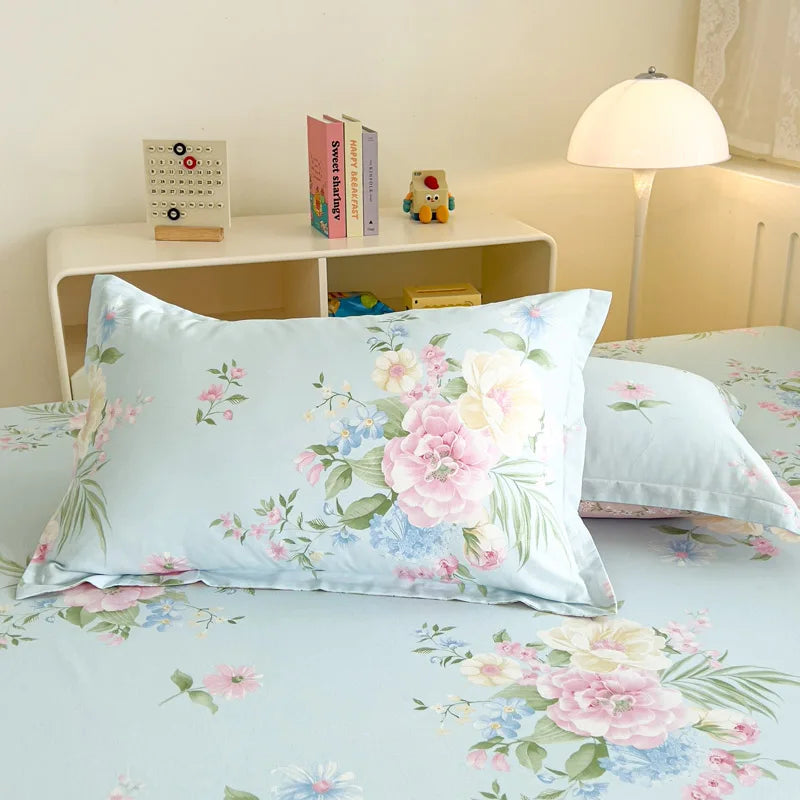 Chambre aux tons pastel avec linge de lit fleuri et décorations diverses sur une étagère.