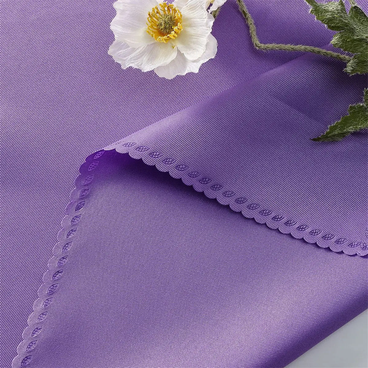 Une fleur blanche épanouie posée sur un fond violet avec une bordure ondulée.