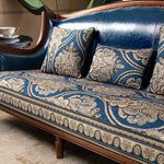 Un fauteuil élégant avec un revêtement bleu paon orné de motifs floraux et géométriques dorés, créant une atmosphère luxueuse et raffinée dans l'espace.