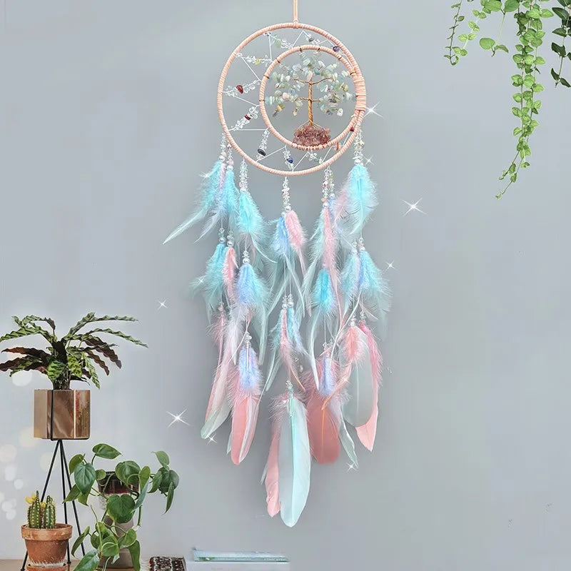 Un capteur de rêves décoratif en macramé avec des plumes roses et bleues, suspendu dans un décor végétal.