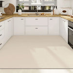 Cette cuisine moderne et épurée présente des meubles blancs et un plan de travail en bois clair, offrant un espace de rangement et de préparation fonctionnel.