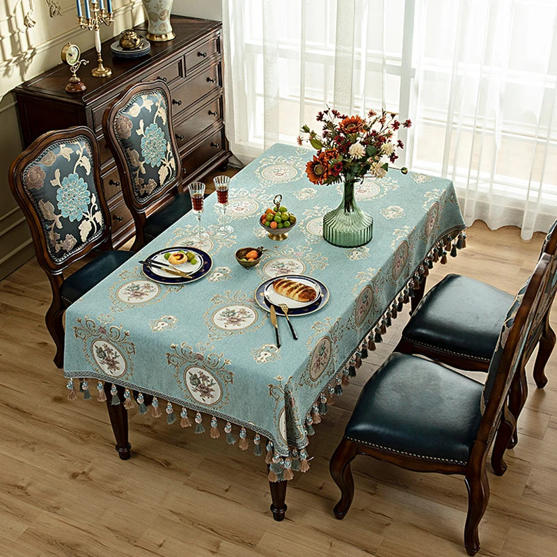 Une table à manger élégante, aux motifs floraux, ornée d'un bouquet coloré, de fruits et de vaisselle posés avec soin, créant une ambiance chaleureuse et invitante dans cette pièce meublée avec goût.