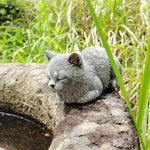 ornement zen statue chat gris allongé texture pierreuse jardin fleurs plantes