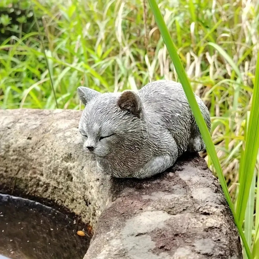 ornement zen statue chat gris allongé texture pierreuse jardin fleurs plantes
