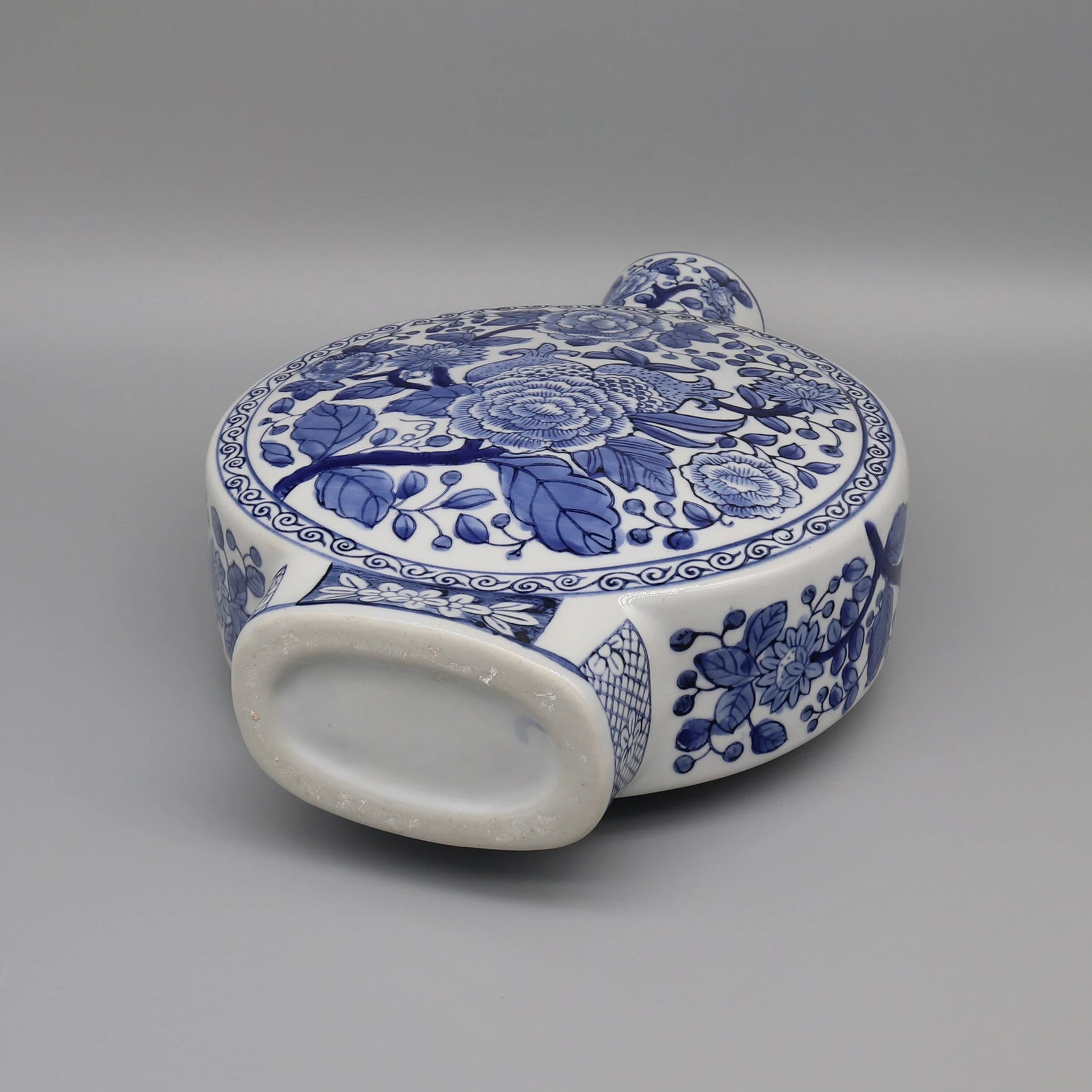 Boîte décorative en céramique bleu et blanc avec des motifs floraux élaborés.