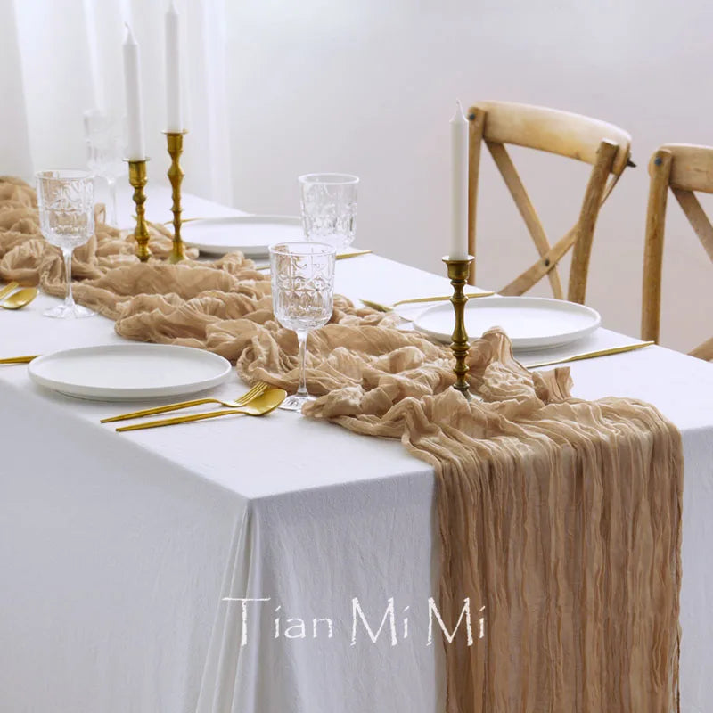 Cette image présente une table de salle à manger élégamment dressée avec des chandelles, des verres et une nappe de couleur beige, créant une ambiance chaleureuse et raffinée.