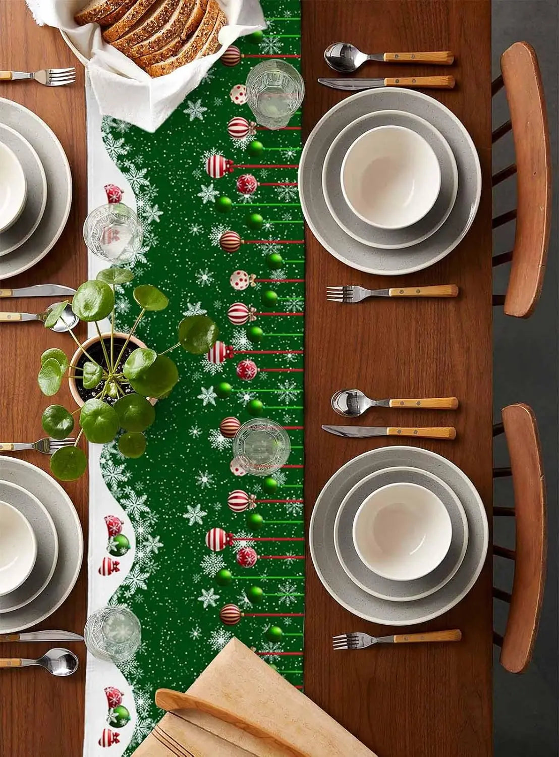 Une belle table de Noël joliment décorée de motifs festifs verts et blancs, avec une mise en place soignée d'assiettes, de couverts en bois et d'accessoires en verre.