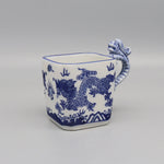 Cette tasse en porcelaine blanche et bleue est décorée d'un motif de dragon stylisé, offrant une touche d'exotisme oriental.