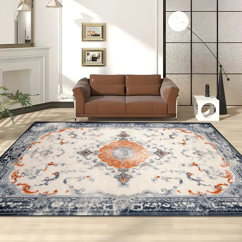 Un tapis de salon décoratif aux motifs floraux et aux couleurs chaudes, posé sur un sol clair dans une pièce avec un canapé en cuir brun et des éléments de décoration murale.