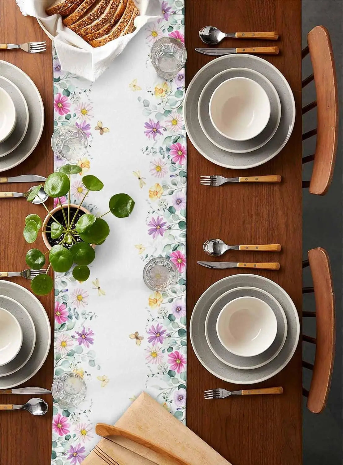 Une belle table de cuisine décorée avec des assiettes, des couverts et une nappe colorée avec des fleurs.