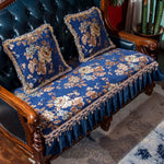 Luxueuse banquette tapissée de motifs floraux bleu foncé et dorés, rehaussée de volants et de franges, offrant un style élégant et vintage dans un cadre d'ameublement classique.