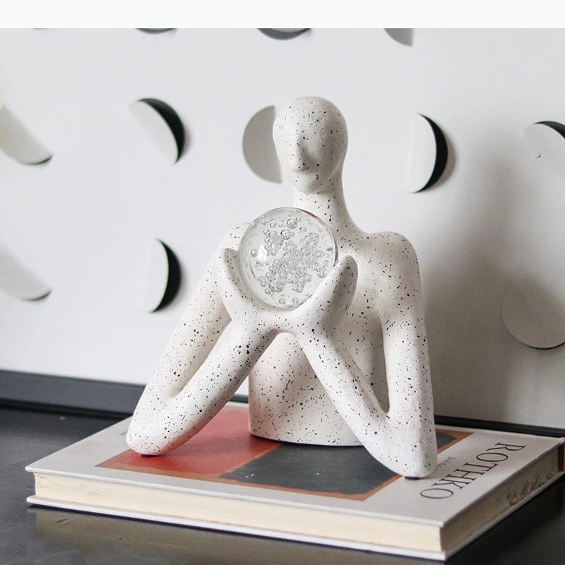 statue décorative personnage humain sphère transparente motifs internes neige cristaux blanc taches noires.texture granuleuse