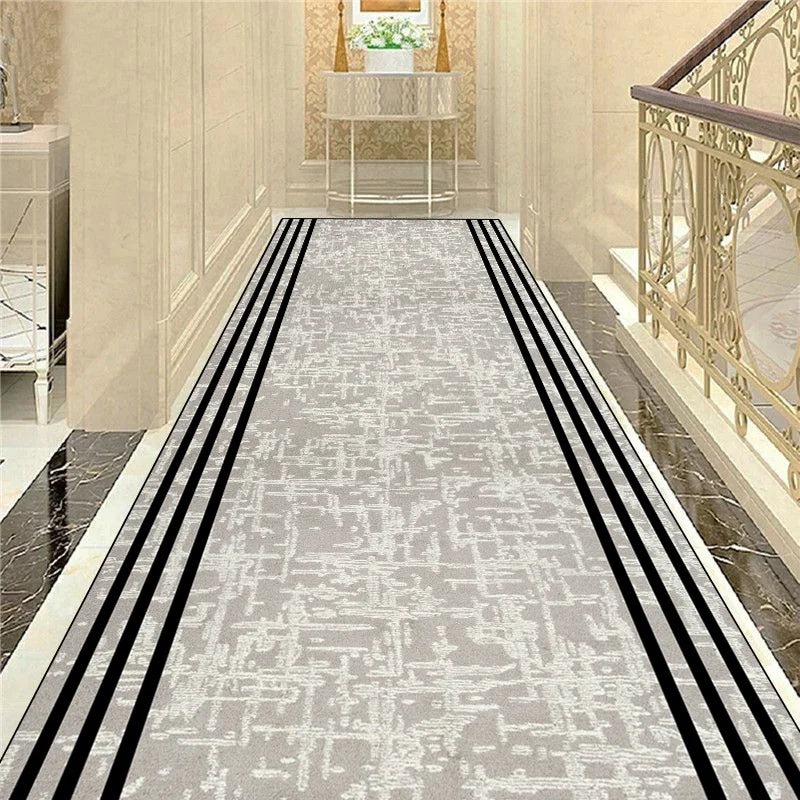 Le sol du couloir est recouvert d'un tapis gris aux motifs subtils, avec de fines bandes noires qui traversent sa longueur, créant un design élégant et sophistiqué dans cet espace.