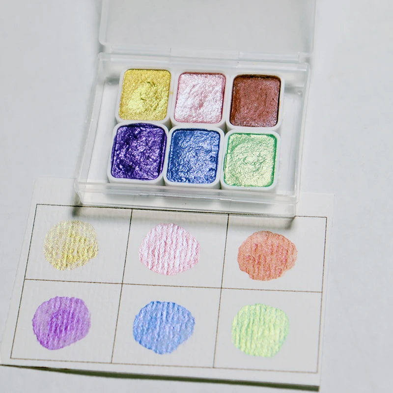 peintures aquarelle palette compacte bleu vert violet rose beige jaune blanc texture granuleuse opaques