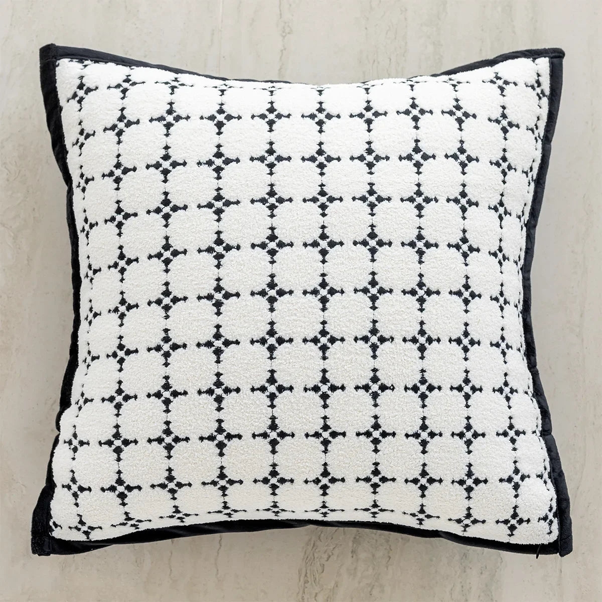 Coussin décoratif noir et blanc orné d'un motif géométrique répétitif.
