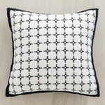 Coussin décoratif noir et blanc orné d'un motif géométrique répétitif.