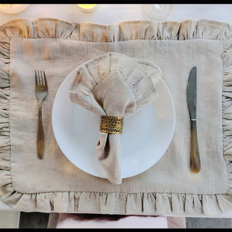 Une table élégante avec une nappe décorée de volants et une vaisselle blanche simple, accompagnée d'un couteau et d'une fourchure dorés.