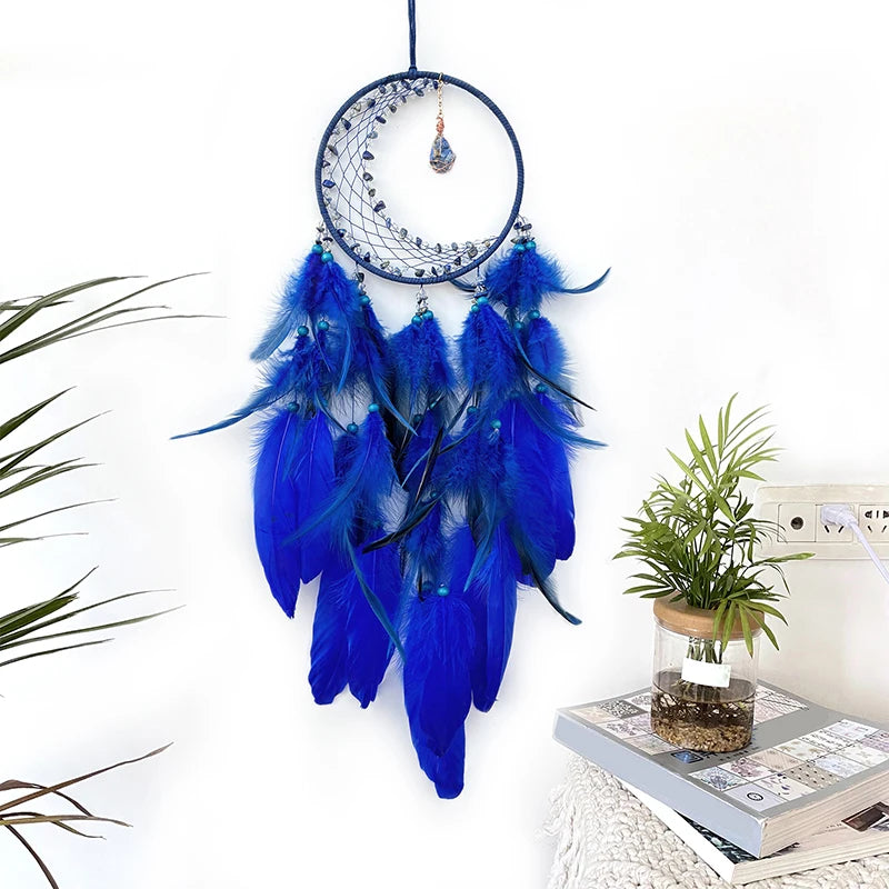 Un attrapeur de rêves bleu foncé orné de plumes bleu électrique, suspendu au mur près d'une plante verte.