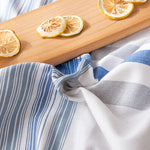 Sur une planche en bois, des tranches de citrons frais et rayures bleues et blanches d'un linge de cuisine.