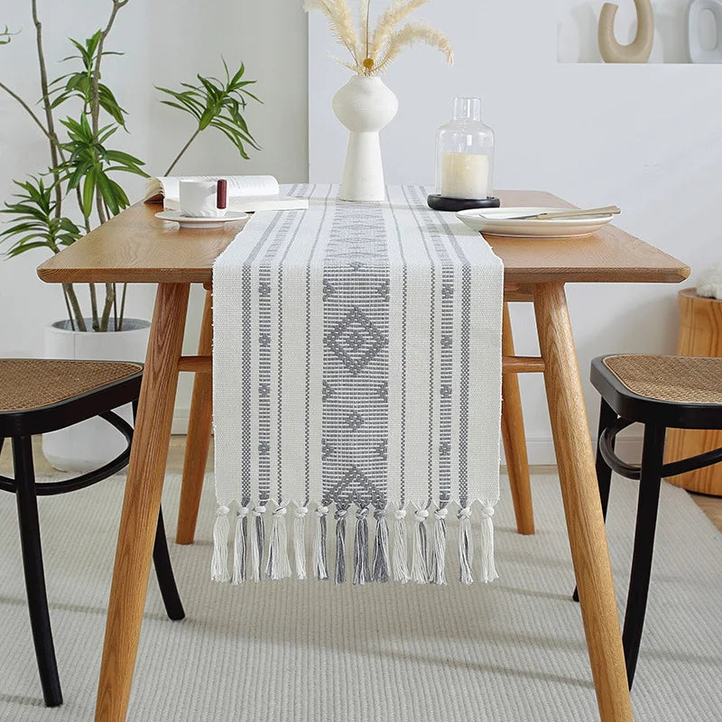 Élégante table à manger en bois avec un chemin de table décoratif et des accessoires de style scandinave.