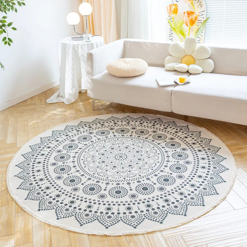 Un tapis rond et décoratif avec un motif de cercles concentriques dans des tons de gris, placé sur un parquet clair dans un salon lumineux et bien aménagé.