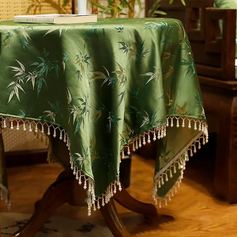 Magnifique nappe verte avec des motifs de feuilles de bambou et des franges de perles, offrant une atmosphère chaleureuse et tropicale à cette table.