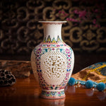 Élégant vase en porcelaine blanche orné de motifs floraux colorés et de perforations délicates, créant un look raffiné et délicat.