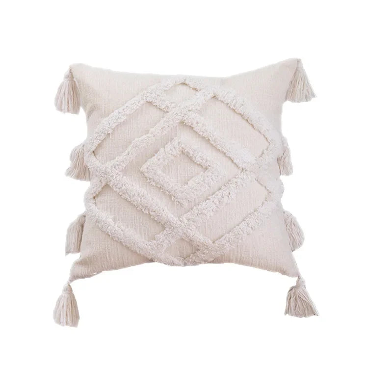 Coussin décoratif en tissu beige délavé avec des motifs géométriques et des franges ornementales, créant une atmosphère chaleureuse et cocooning dans un intérieur contemporain.