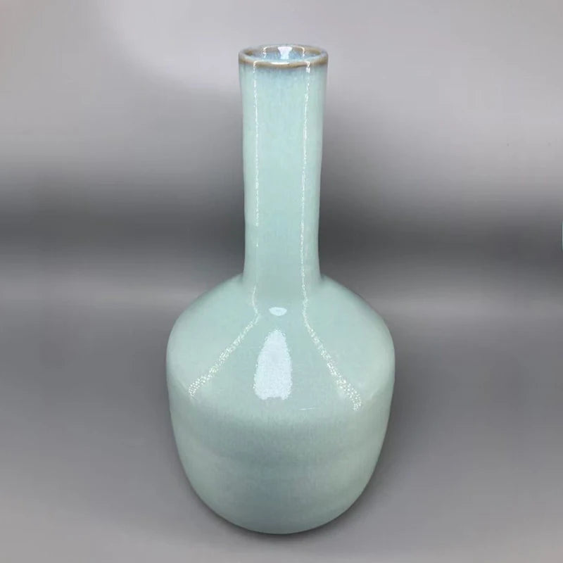 Vase en céramique de couleur vert pastel avec un col étroit et une forme élancée.