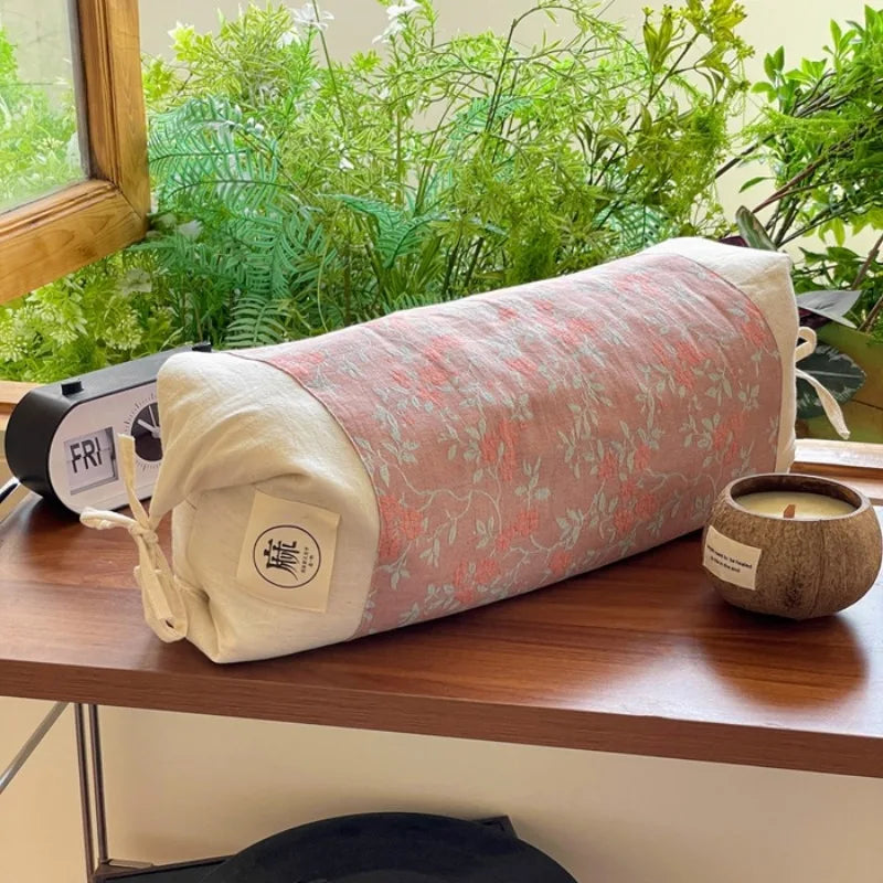 Un rouleau de yoga coloré et décontracté, entouré de plantes vertes épanouies, suggère un environnement serein et apaisant pour la pratique du yoga.