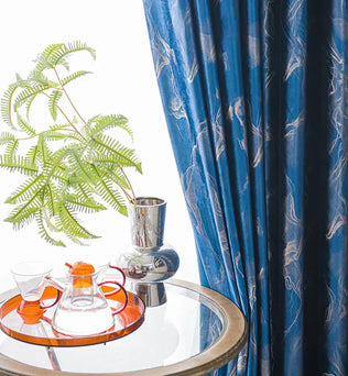 Rideau bleu foncé à motifs modernes avec une table en verre et vase chromé décoratif