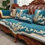 Un canapé en cuir brun richement décoré avec des motifs dorés, orné de coussins bleu-vert à motifs élaborés, créant une atmosphère de luxe et d'élégance dans cette pièce.
