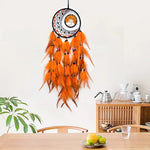 Le magnifique attrape-rêves orange avec des plumes suspendues à un support circulaire crée une belle décoration murale aux tons chauds.