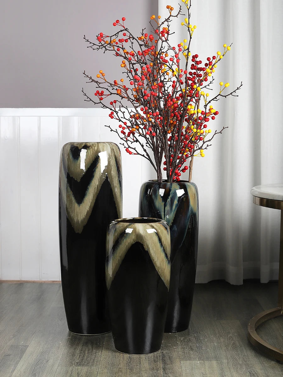 Vases en céramique noir et or avec branches et baies colorées créant une décoration élégante et automnale.