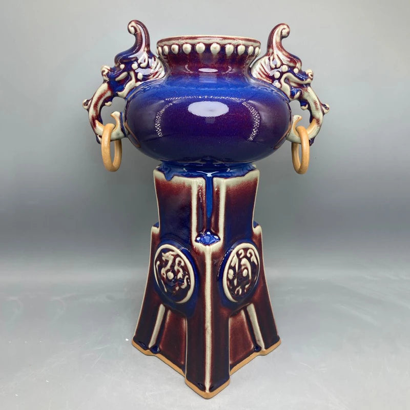 Un vase décoratif en céramique de style antique avec des motifs floraux et des ornements en relief, dans des tons de bleu et de brun, évoquant une ambiance élégante et sophistiquée.