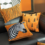 Cette image représente une série de coussins décoratifs avec des motifs graphiques et des éléments naturels, créant une ambiance chaleureuse et rustique dans un intérieur.