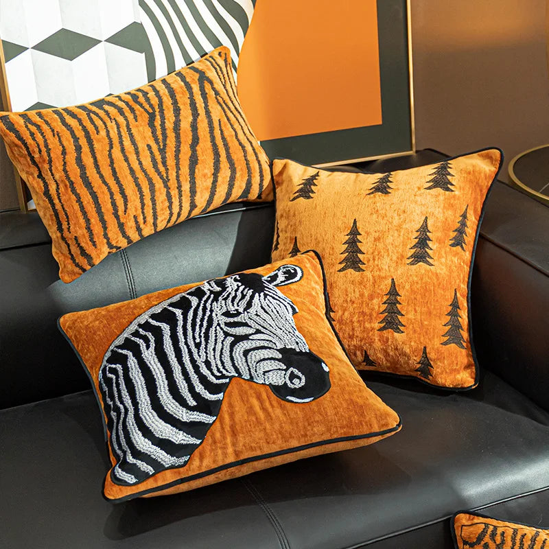 Cette image représente une série de coussins décoratifs avec des motifs graphiques et des éléments naturels, créant une ambiance chaleureuse et rustique dans un intérieur.