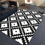 Tapis noir et blanc de style géométrique moderne avec motifs carrés et losanges dans une pièce avec un canapé et un décor minimaliste.