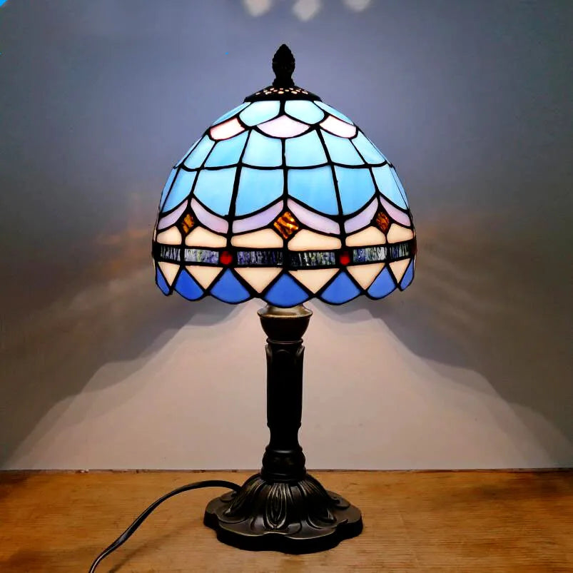 Lampe de chevet Tiffany allumée créant une lumière chaude dans une chambre