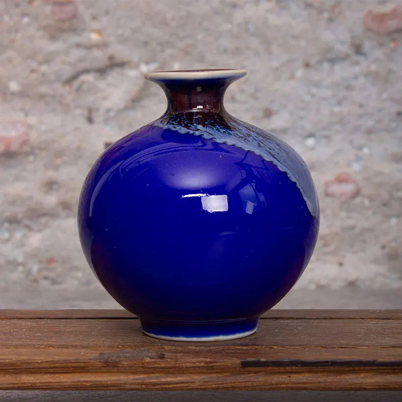 Un vase en céramique d'un bleu intense, posé sur une surface en bois rustique, reflétant la lumière de manière élégante.