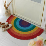 Un tapis demi-lune coloré et arc-en-ciel avec des accessoires boho stylés posés à côté.