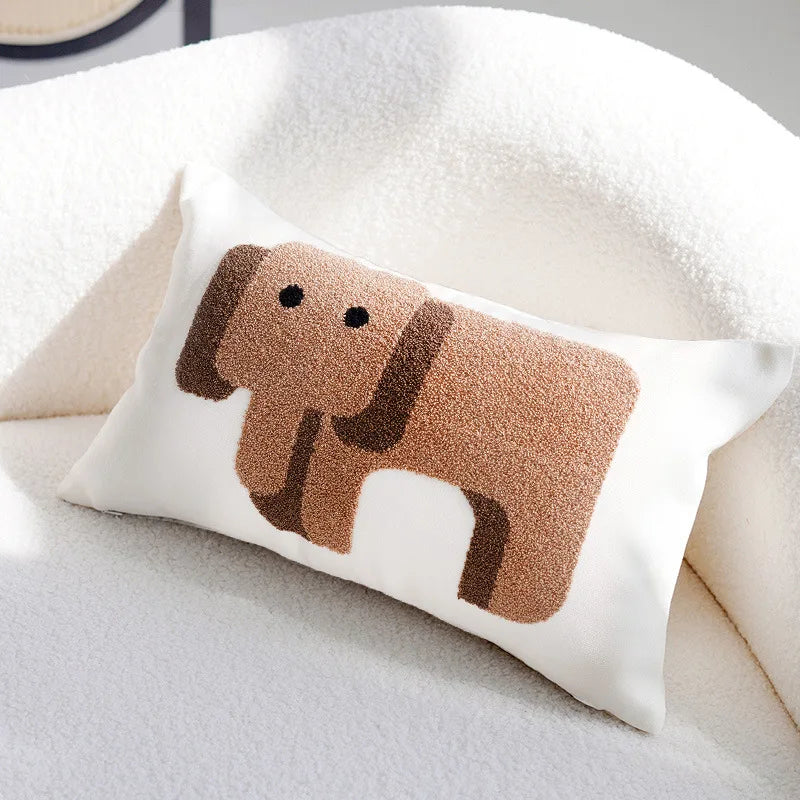 Coussin en forme de petit chien beige décoré sur un lit blanc moelleux.