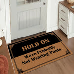 Tapis d'entrée humoristique utilisé sur un porche extérieur avec plantes