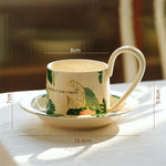 Tasse en porcelaine avec fleurs et motifs de feuilles, accompagnée d'une soucoupe, créant un ensemble élégant pour la dégustation d'une boisson chaude.