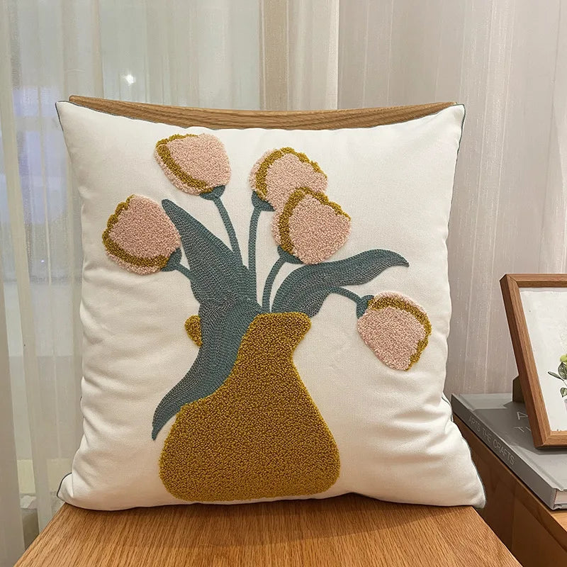 Coussin décoratif avec un motif floral stylisé en tons pastel sur un fond blanc crème, créant une atmosphère chaleureuse et apaisante.
