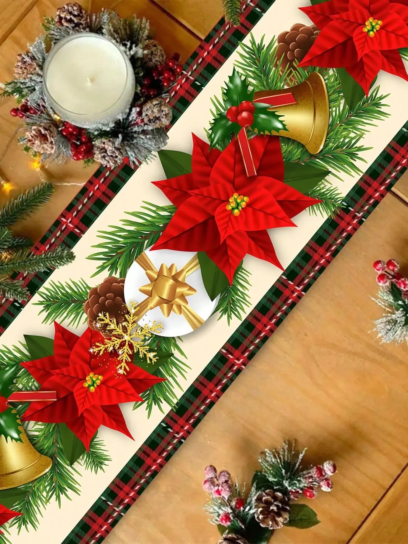 Une décoration de Noël festive avec des fleurs de poinsettia rouges, des branches de sapin, des cônes, une bougie et des ornements dorés sur un fond de tartan.