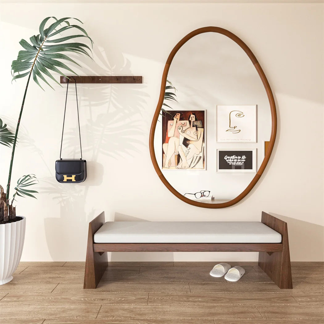 Un banc en bois rustique avec un miroir ovale et une décoration murale minimaliste, créant un espace accueillant et épuré.
